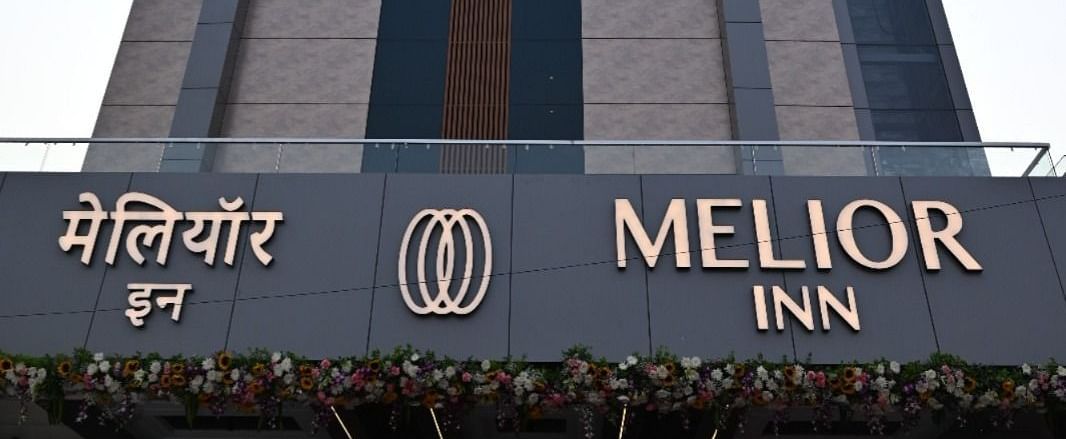 A tall building with a sign reading 'Melior Inn' at its base is shown against a partly cloudy sky.