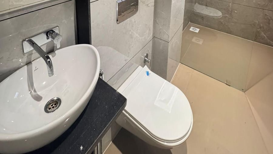 Well-appointed bathroom at Hotel Mumbai House, Vijay Nagar, Indore, fitted with a glass shower enclosure, stylish sink, and modern amenities.