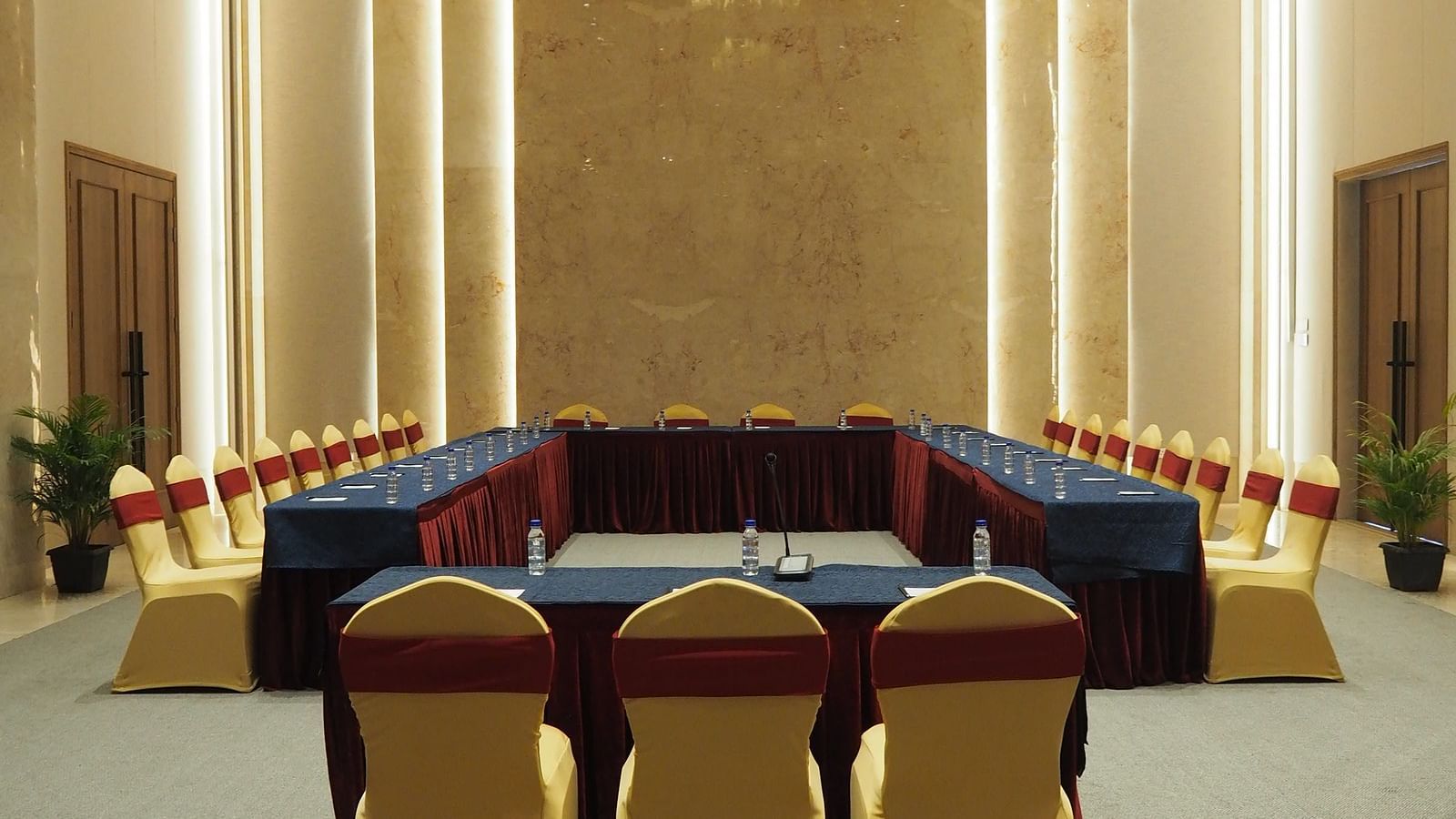 A formal meeting room with a long table and yellow chairs, under a chandelier - Club Charholi, Pune 