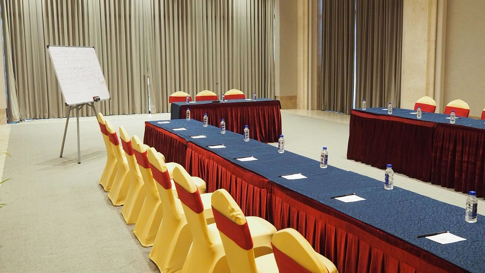 A long table with yellow chairs in a large, well-lit conference room - Club Charholi, Pune 