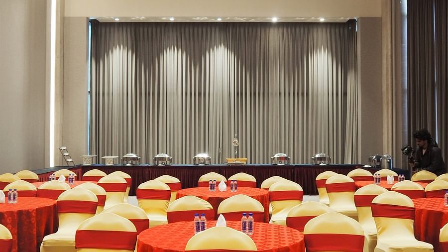 A wide view of a hall with rows of chairs facing a stage with curtains - Club Charholi, Pune 