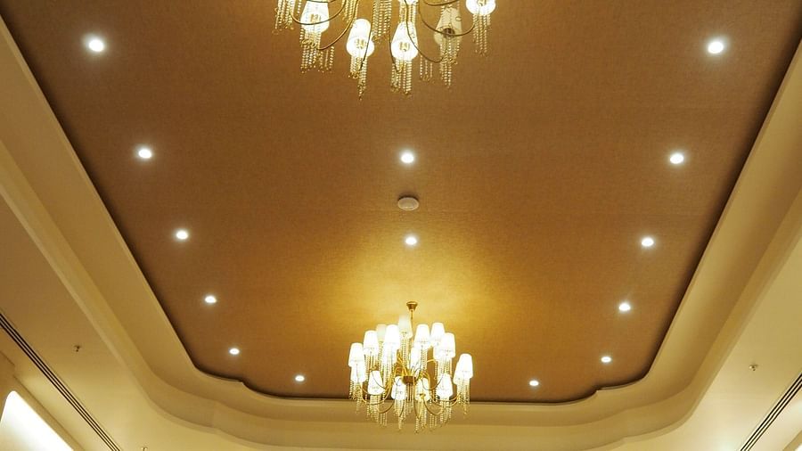 An ornate ceiling with a chandelier in a grand, symmetrical hall - Club Charholi, Pune 