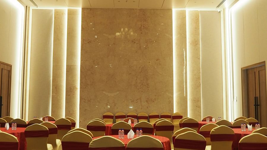 A dining setup with round tables and chairs in a luxurious hall with warm lightings - Club Charholi, Pune 