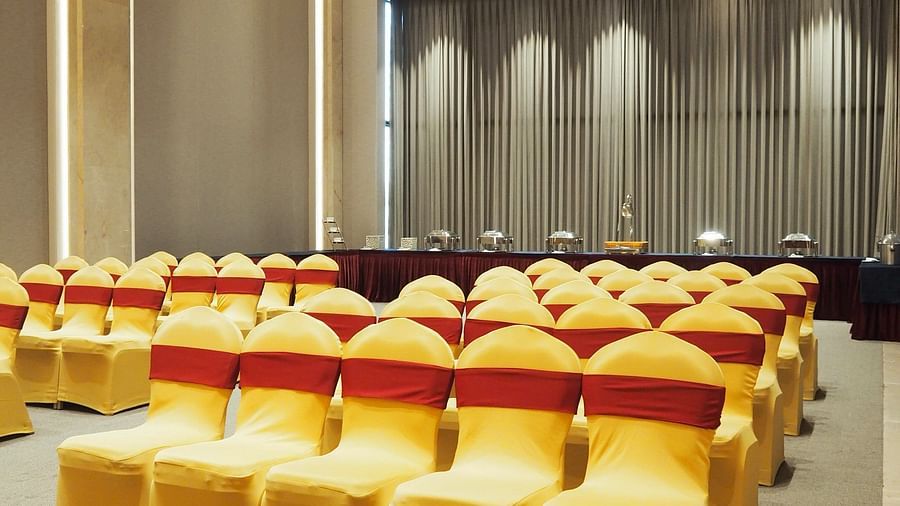 Rows of yellow chairs leading towards a curtained stage in a bright hall - Club Charholi, Pune 