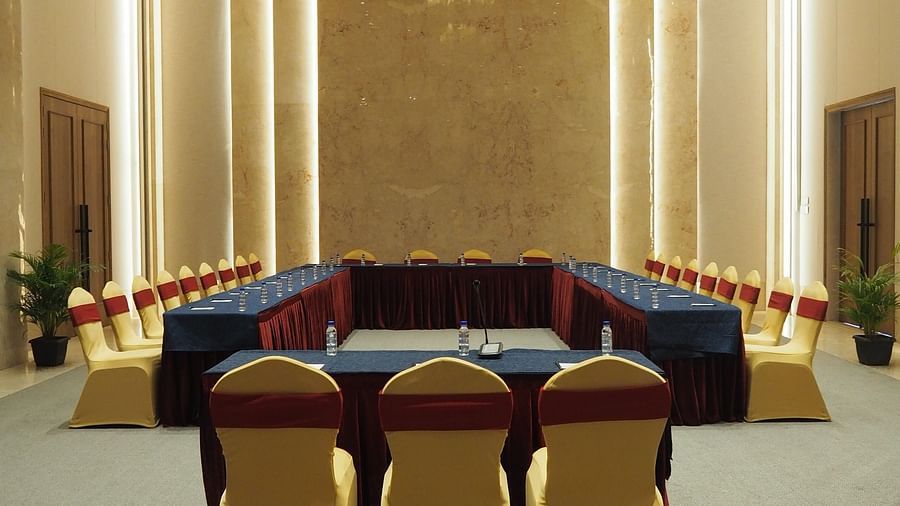 A formal meeting room with a long table and yellow chairs, under a chandelier - Club Charholi, Pune 