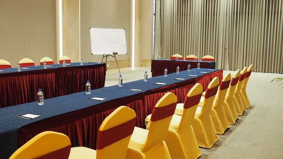 A long table with yellow chairs in a brightly lit, spacious conference hall - Club Charholi, Pune 