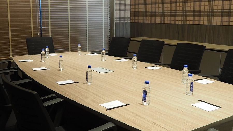 A long meeting table with chairs under a bright light in a room with striped walls - Club Charholi, Pune 