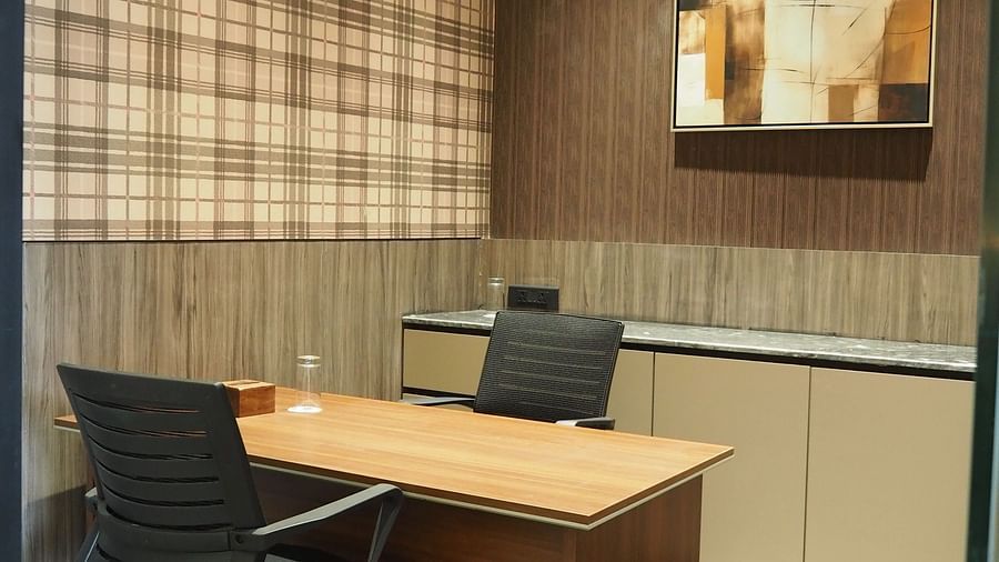 A small desk with a computer and a lamp, against a checkered wall with artwork - Club Charholi, Pune 