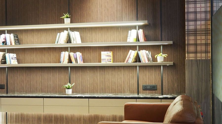 A modern room with two armchairs, a small table, and open shelves on a dark wall - Club Charholi, Pune 