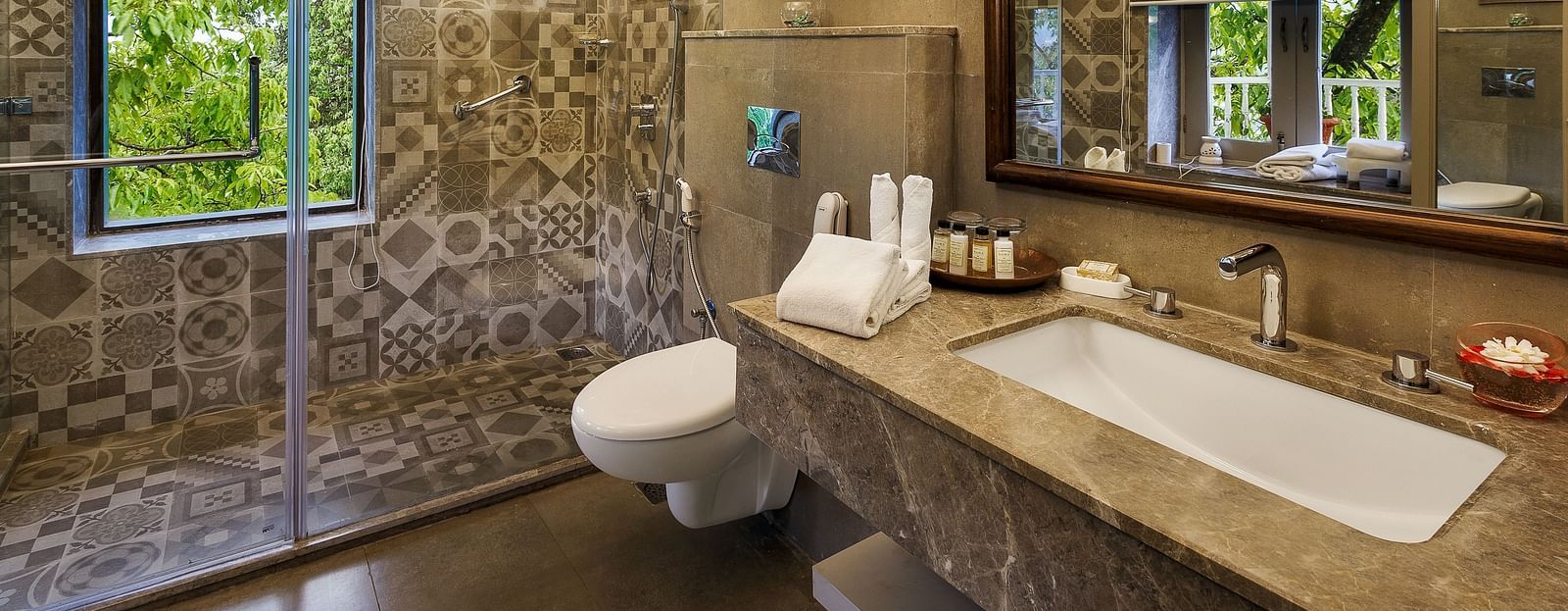 An image featuring a washroom, a big wooden mirror, marble floor and the glass separator for bath area - The Naini Retreat, Nainital.