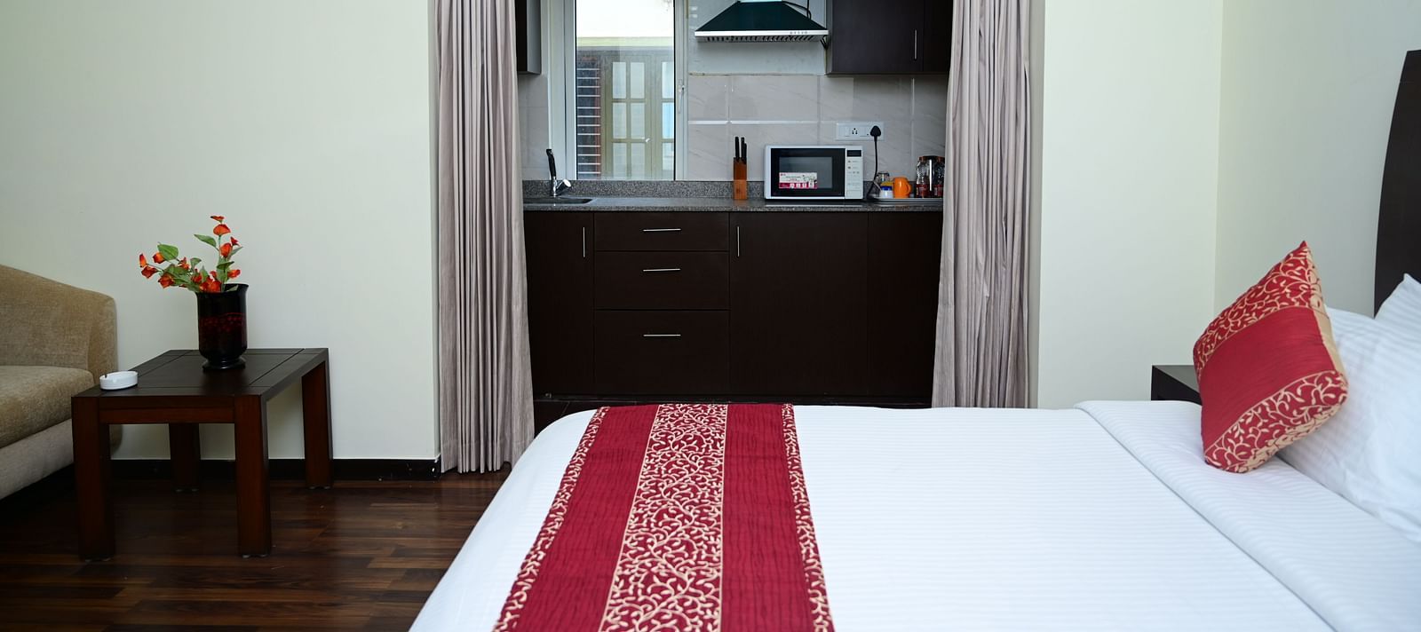 Image of a double bed with pink bedsheet and a kitchen visible from the Executive Suite at Sterling Keys by TGI
