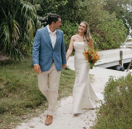 Bride and groom walking hand-in-hand on a pathway flanked by greenery at Casa Morada.