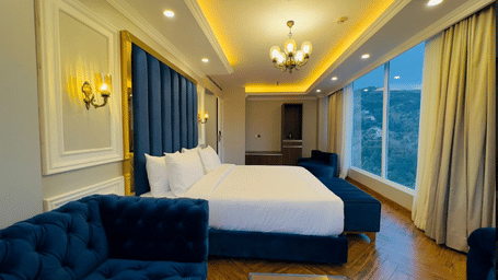 Spacious room with double bed, seating area, elegant lighting, and floor-to-ceiling glass windows at Claret Inn, Dalhousie. 