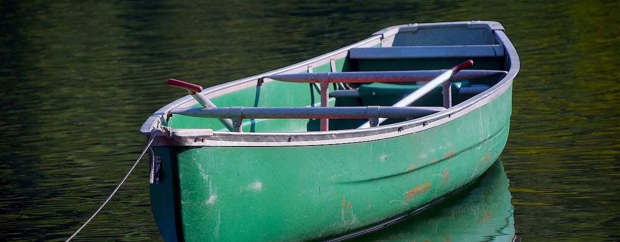 Close-up of an empty boat gently floating on calm water, reflecting the serene surroundings.