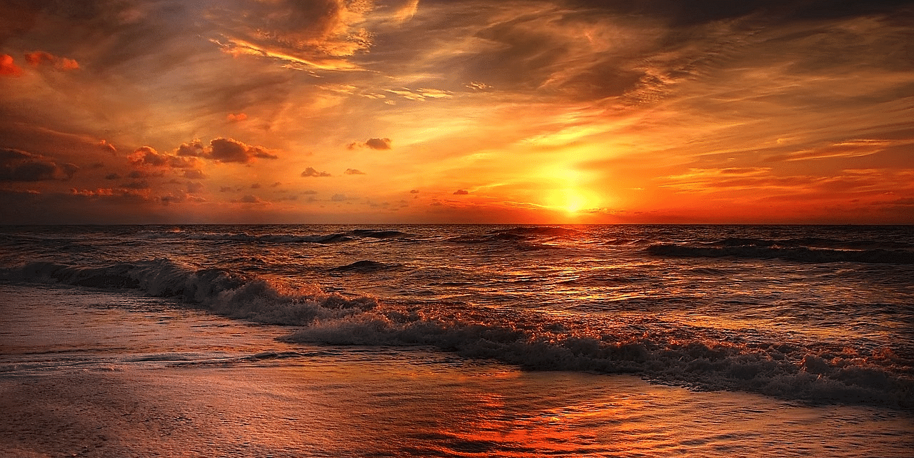 Stunning sunset over the beach with dark clouds painting the evening sky
