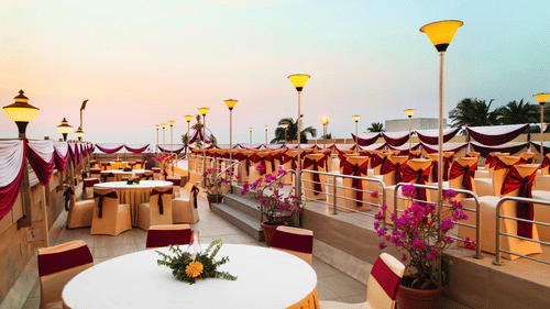 An image of the rooftop banquet hall with round tables, chairs and beautiful decoration - Ramada Plaza by Wyndham Palm Grove