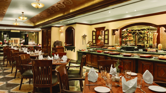 Tangerine Cafe featuring tables and chairs with warm lighting - Ramada Plaza by Wyndham Palm Grove