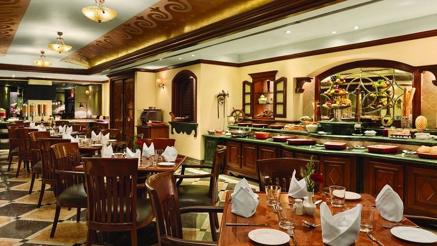 An image of the Tangerine Cafe featuring tables and chairs with warm lighting - Ramada Plaza by Wyndham Palm Grove