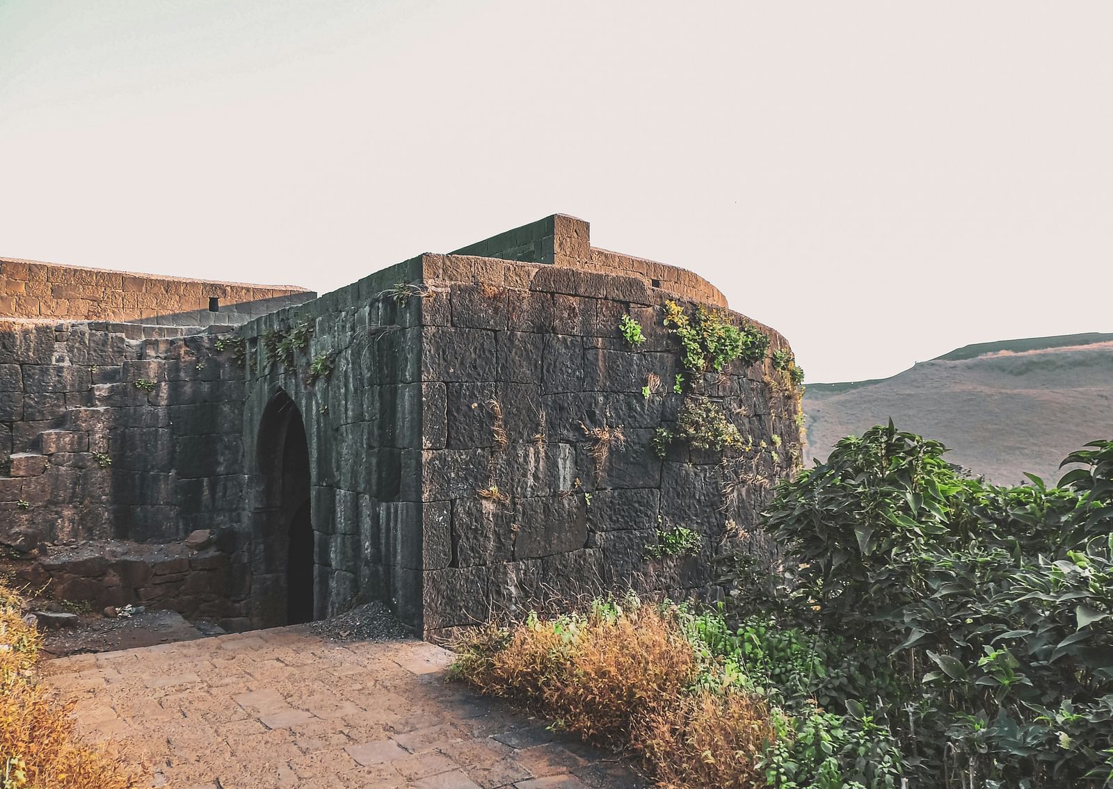 An overview of an ancient fort on top of a hill with vegetation around it.