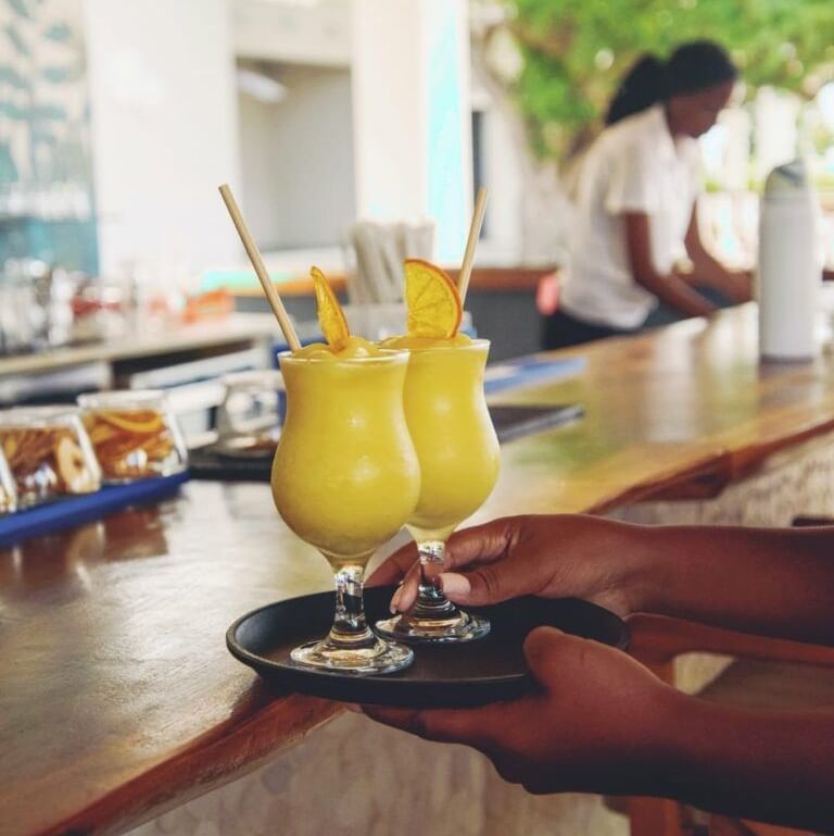 A bartendar serving cocktails in an outdoor bar area.