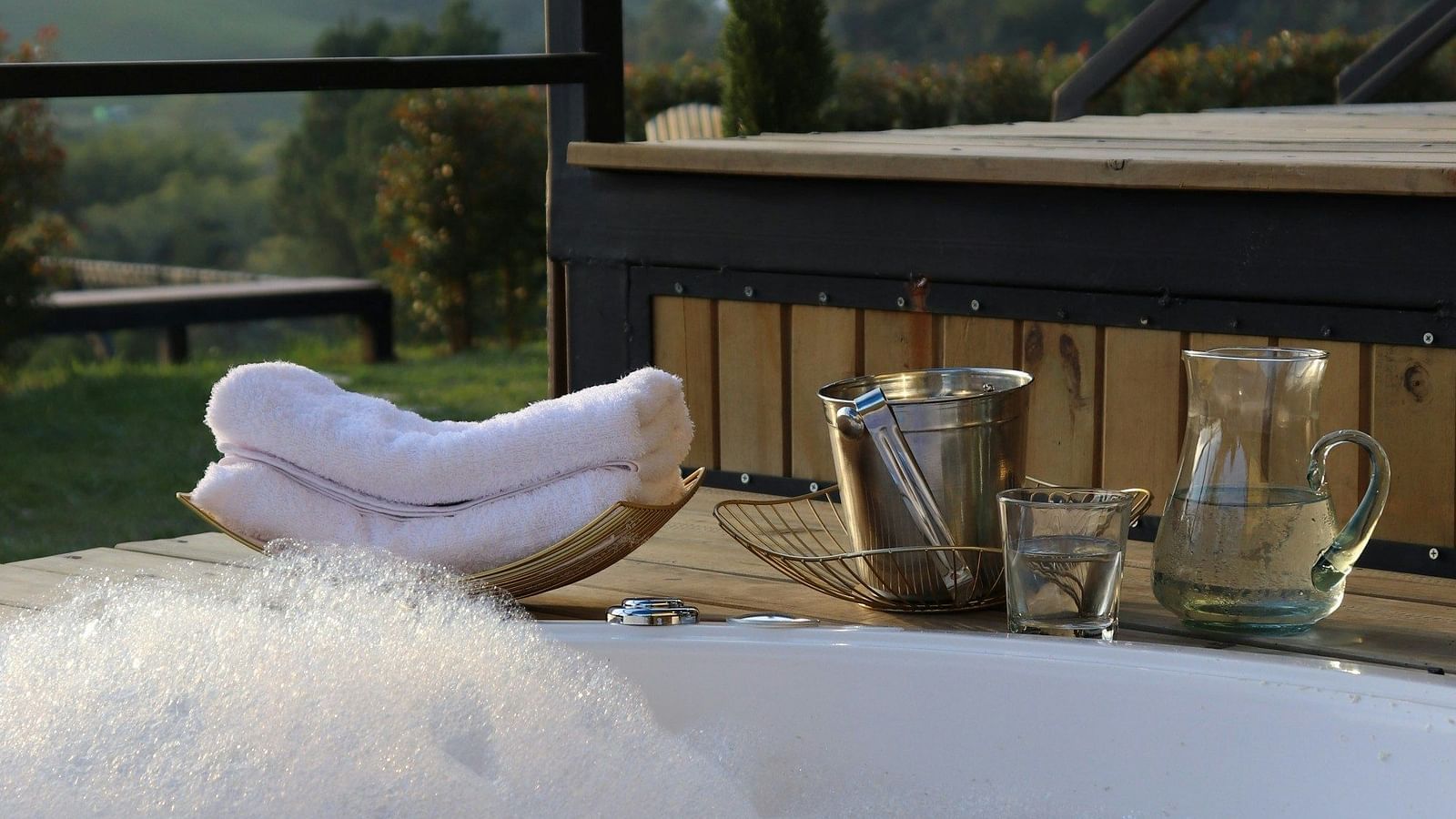 Outdoor Jacuzzi setup with towels and champagne in a serene setting.