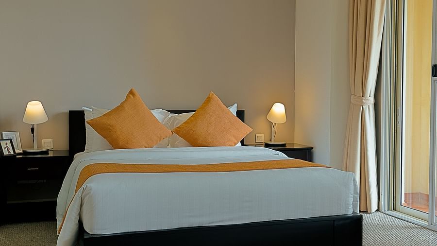 A bedroom with a bed, nightstand, and curtains | Penthouse | Central Mansions, Phnom Penh