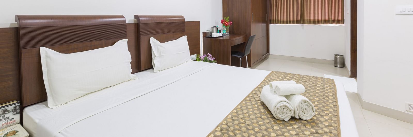 A room with a double bed, a patterned bed runner, a work and a chair, and a wardrobe - Sanctum Suites BEL Road, Bangalore