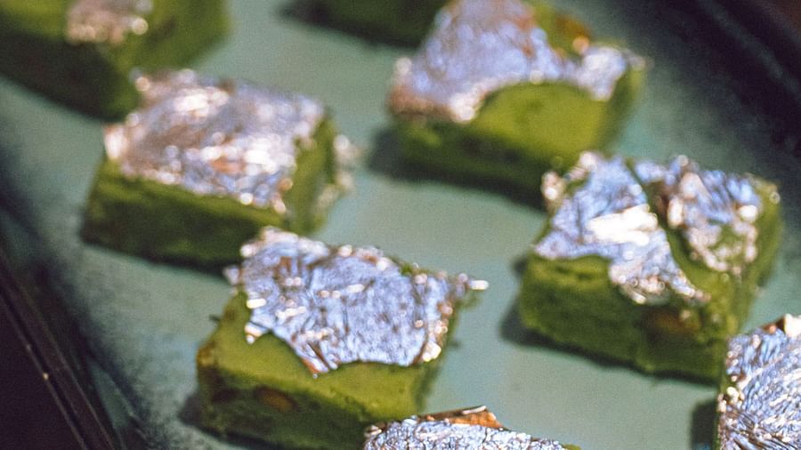 A tray of small, square food items, possibly desserts or appetizers, with a light topping.