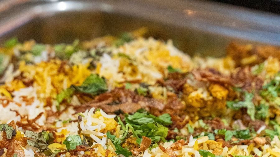 A metal tray filled with a rice dish mixed with vegetables and possibly meat.