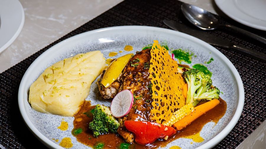 A plate of food with a piece of fish, vegetables, and a sauce.