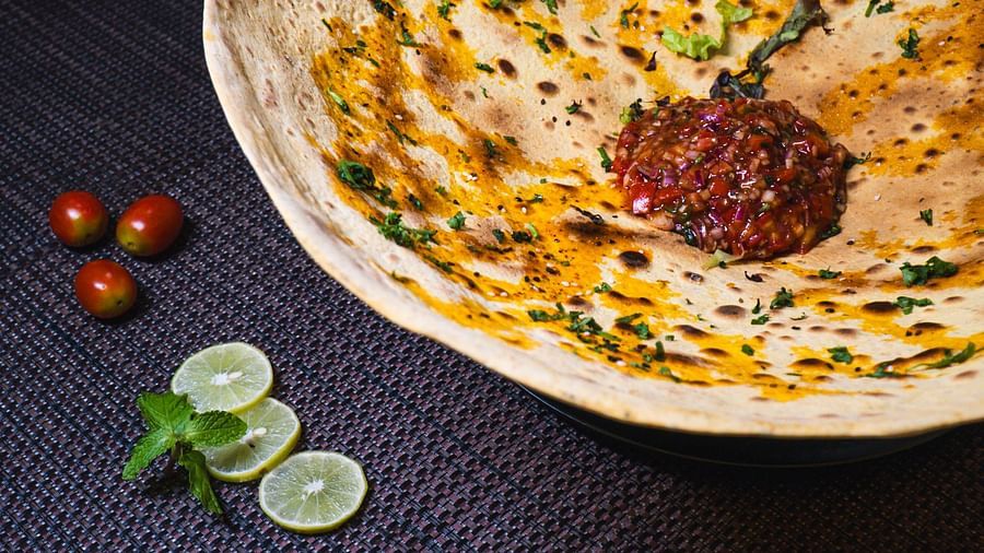 Flatbread with toppings on a dark surface, accompanied by small round objects.