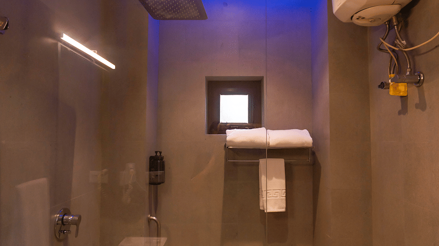 A modern resort bathroom featuring a glass walk-in shower with rainfall shower head and blue mood lighting - Wood Castle Spa & Resort, Jim Corbett