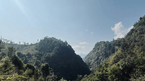 a trail during Mawryngkhang Trek with mountain in view and blue sky in the background