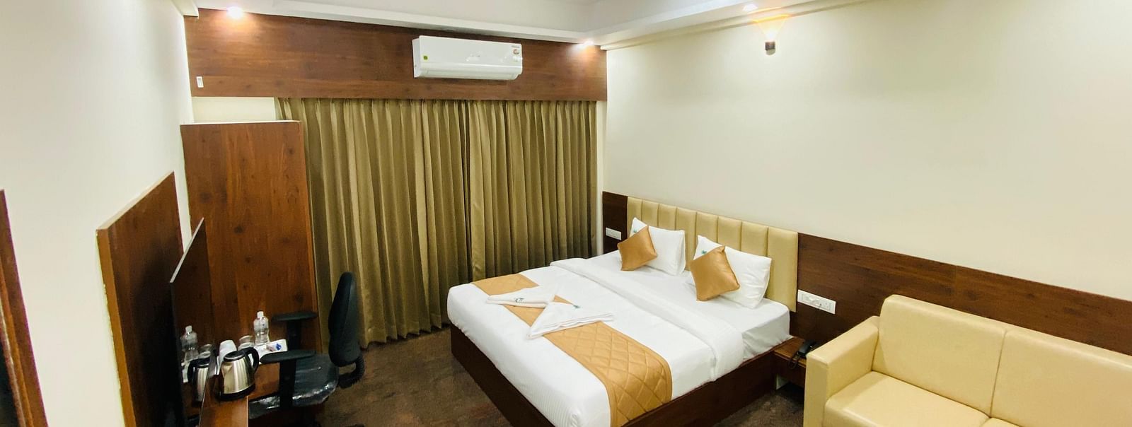 Relaxing room setup with wood finishes, golden linen, and a reading chair at Hotel Sahara Tree.
