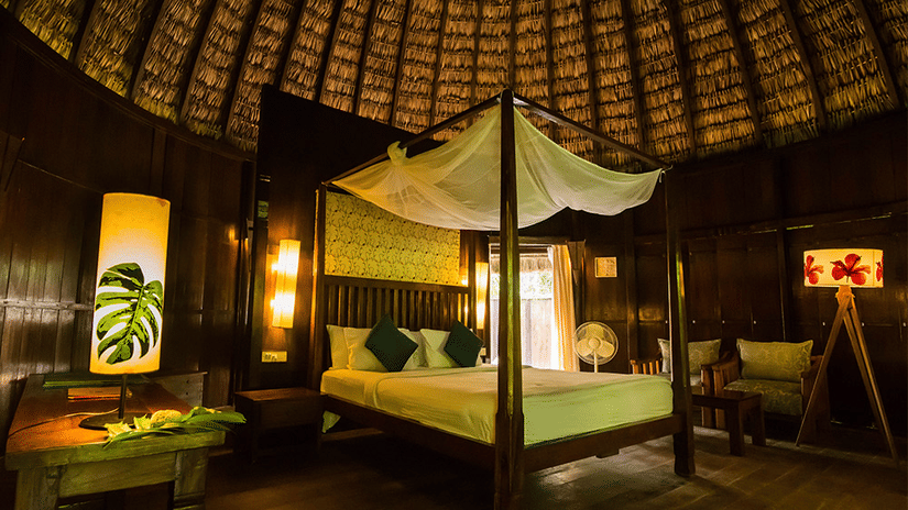 Rustic wooden cottage with a 4-poster bed and warm interiors at Barefoot at Havelock Island Resort