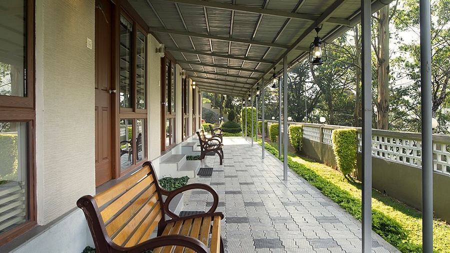 Covered walkway with wooden benches and a tiled floor - Abad Copper Castle, Munnar