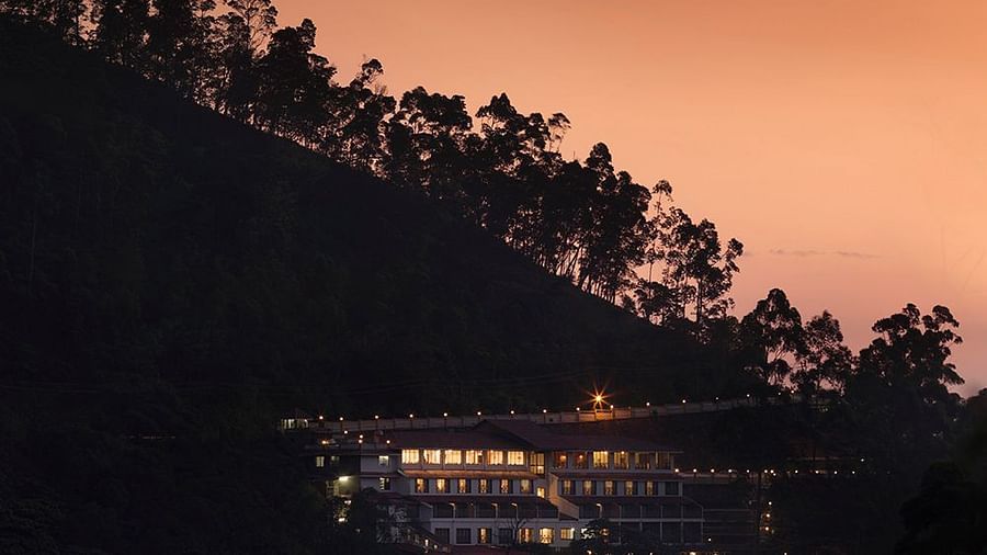 Abad Copper Castle resort at dusk, silhouetted against a warm, orange-tinted sky.