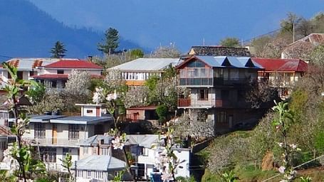 Cluster of hillside homes in a mountain village, with colourful rooftops and terraced gardens nestled in the hills.