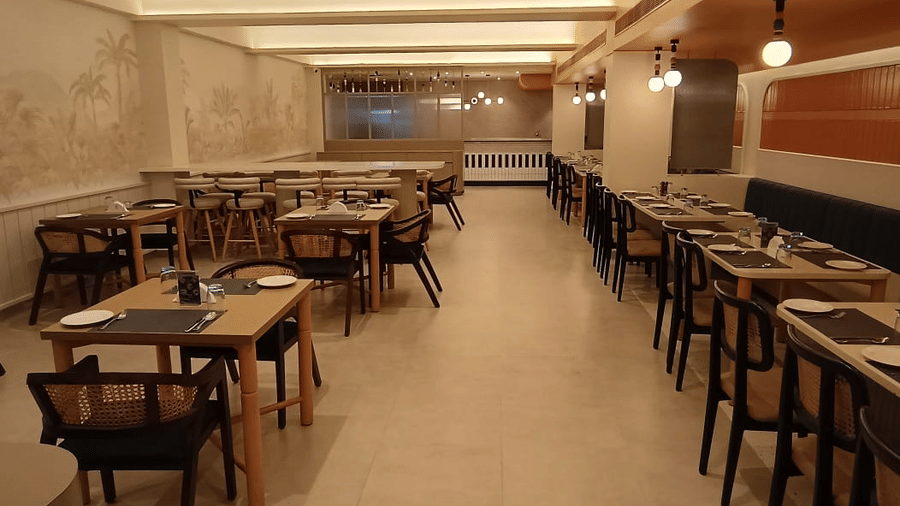 An extended view of the interior of Hotel Manorath showcasing neatly organised dining tables, cutlery and warm lighting at Lords Eco Inn in Belagavi.