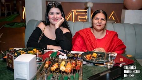 Guests posing for a photo with a spread of barbecue food in front at Themis Barbecue House, Ambala