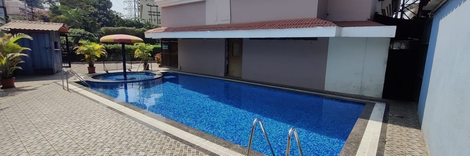 Outdoor swimming pool of Highland Resort featuring a spacious pool deck, and a children's pool canopied by an umbrella.