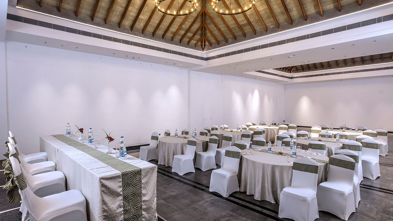 Another angle of the banquet hall with round tables and chairs | Great Trails Wayanad by  GRT hotels.