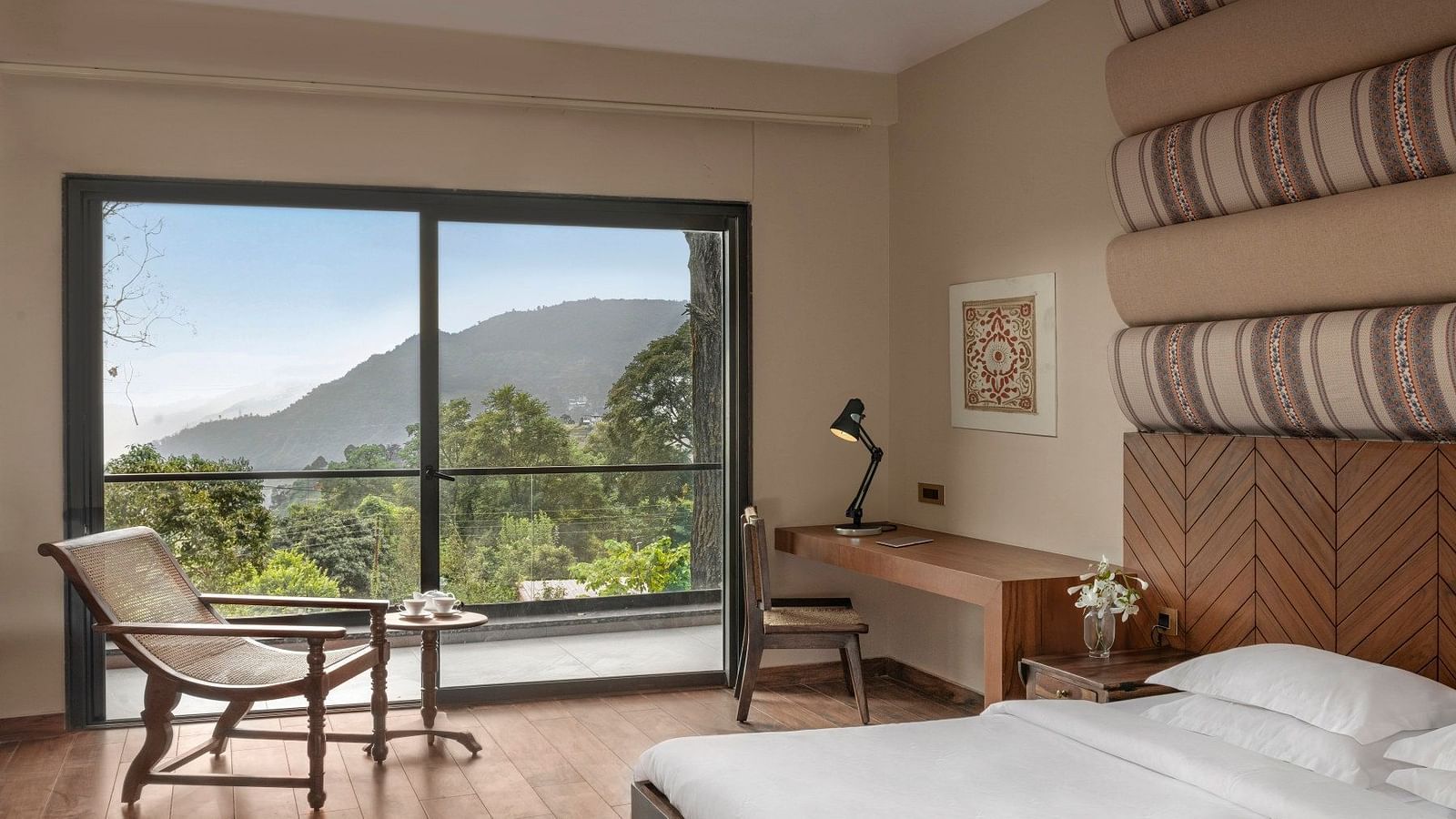 A modern room with a large glass window offering a scenic mountain view, stylish desk space, and minimalist decor - The Samai, Bhimtal