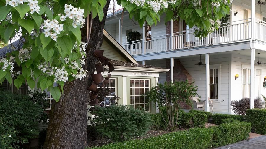 A view of Riffe's Meeting House at Tallman Hotel surrounded by a tall tree and bushes.