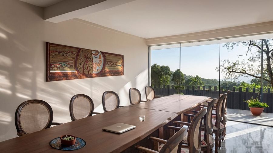 A meeting room with a long table in front of a glass door opening to a lush green garden - The Samai, Bhimtal
