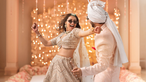 Bride dancing with her husband to be in a ceremony. The place is decorated with flowers and fairy lights.