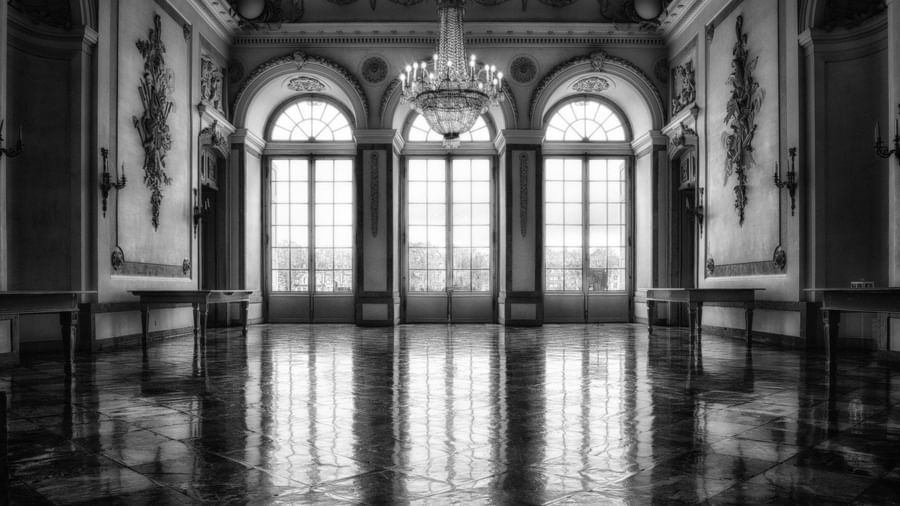 A black and white view of the interiors of a castle with floor to ceiling windows.