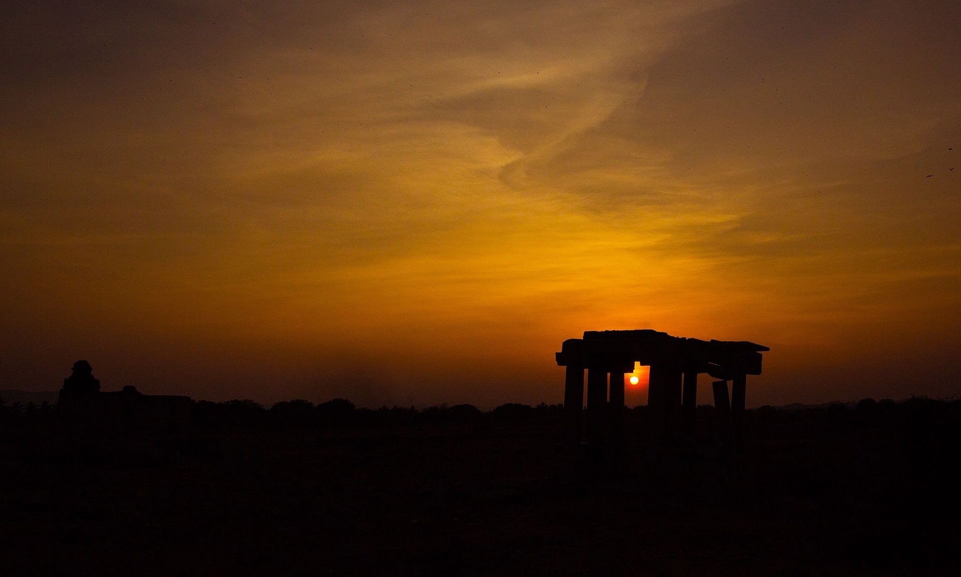 Sunset silhouetting ruins on Hemakuta Hill, Hampi.