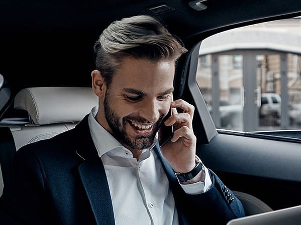 A person wearing a black suite attending a call while travelling in a car - S Hotel Montego Bay, Jamaica