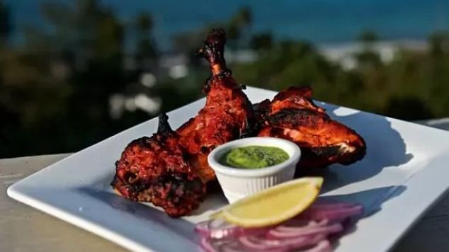 Plate of grilled tandoori chicken with onions, lemon, and chutney in front of ocean | A Stone's Throw Away
